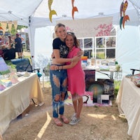 two women hugging in front of a tent